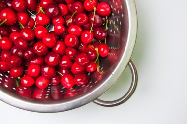 beyaz zemin üzerine kevgir içinde taze kiraz