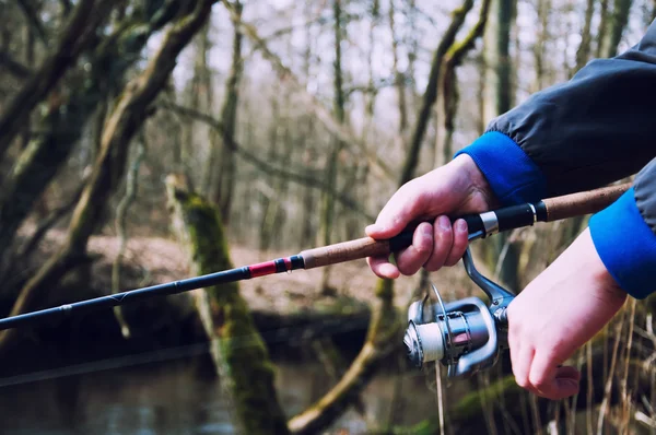 Mão segurando uma vara de pesca com carretel — Fotografia de Stock