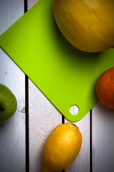 Früchte auf grünem Schneidebrett, weißer Tisch — Stockfoto