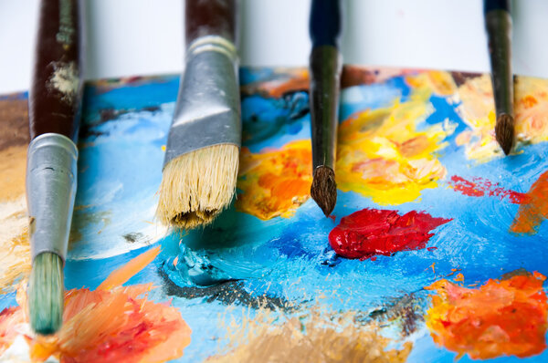 Палитра с кисточками на белом фоне
