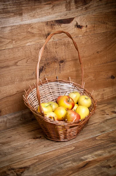 Korb mit Äpfeln auf Holzgrund — Stockfoto