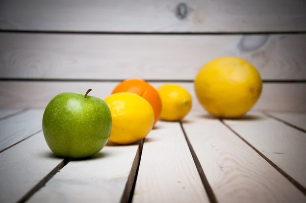 Früchte in Reihe auf weißem Holztisch — Stockfoto