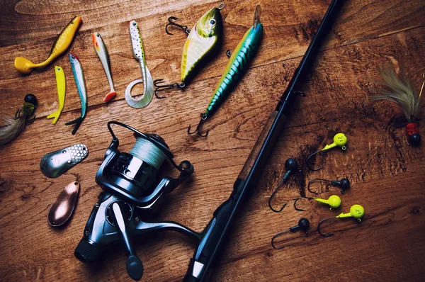 Fishing baits and rod isolated on wooden background