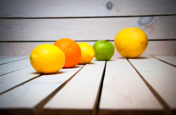 Früchte in Reihe auf weißem Holztisch — Stockfoto