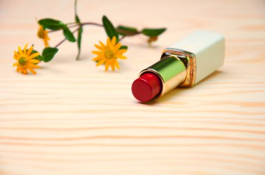 Kırmızı ruj ve ahşap zemin üzerine çiçek