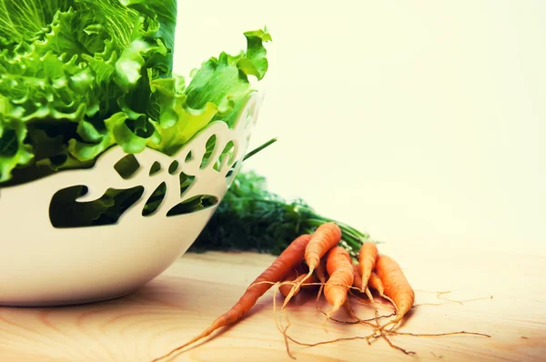 Porkkanat ja salaatti puupöydällä — kuvapankkivalokuva