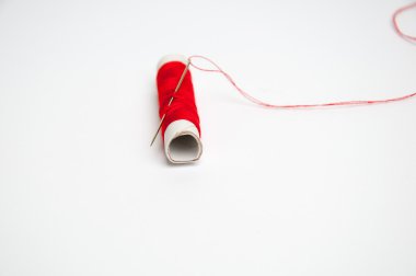 Kırmızı dikiş ipliği ve beyaz arka plan üzerinde izole iğne