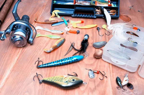 Fishing baits and rod isolated on wooden background