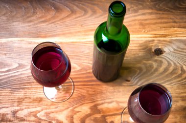 Ahşap arka planda şarap kadehi ve şişe.