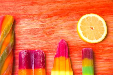 Kırmızı ahşap arka plan üzerinde renkli Buz lolly