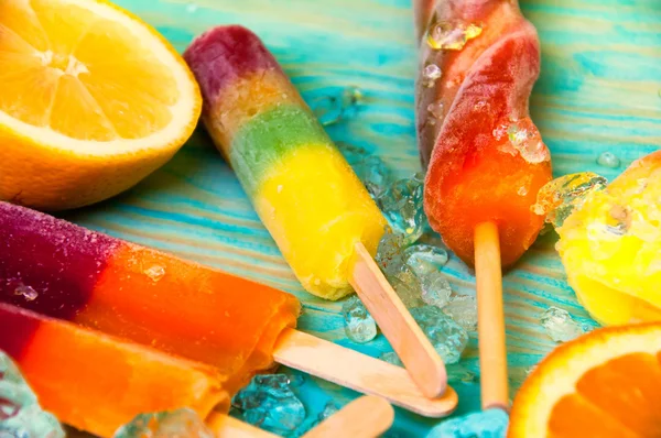 Colorful ice lolly and friuts on blue wooden background — Stock Photo, Image