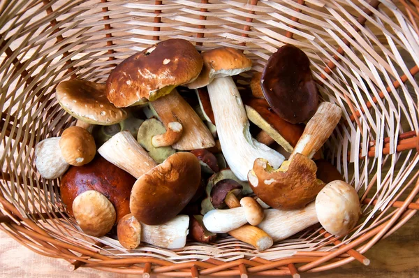 Champignons frais dans le panier sur une table en bois — Photo