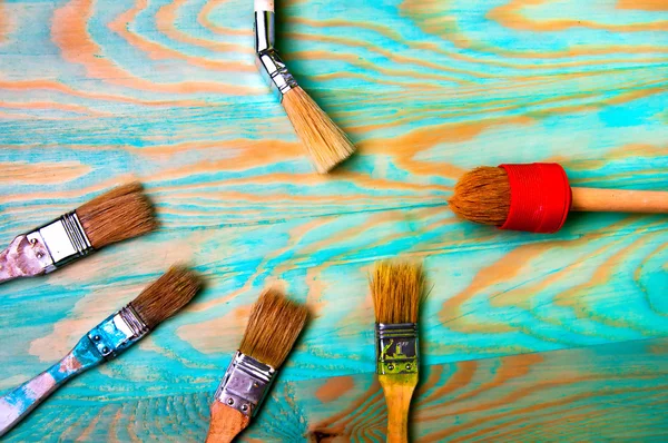 Pędzli malarstwo na niebieskim drewnianym stole — Zdjęcie stockowe