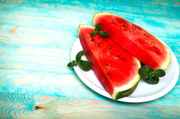Kousky melounu na modré dřevěné pozadí — Stock fotografie