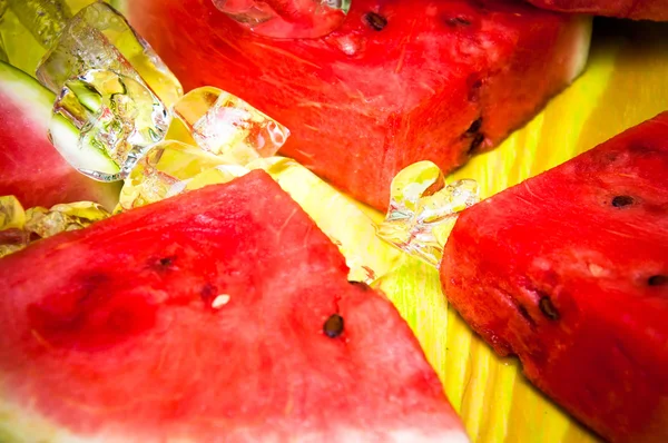 Pieces of watermelon and ice cubes on green wooden background — Stock Photo, Image