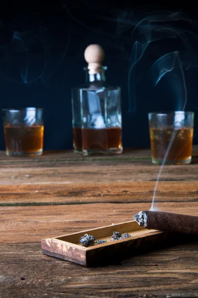 Cigarros y whisky con hielo sobre mesa de madera —  Fotos de Stock