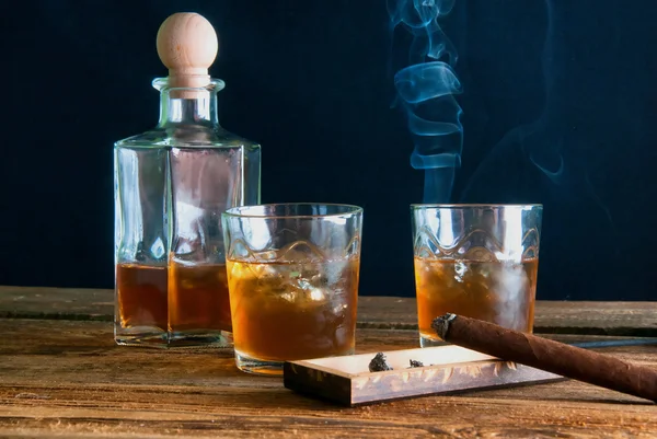 Whisky con hielo y cigarro sobre mesa de madera — Foto de Stock