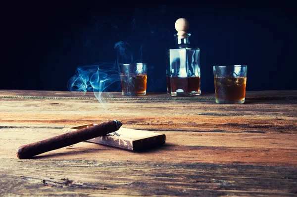 Cigarros y whisky con hielo sobre mesa de madera —  Fotos de Stock