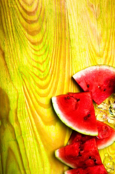 Kousky melounu a kostky ledu na zelené dřevěné pozadí — Stock fotografie