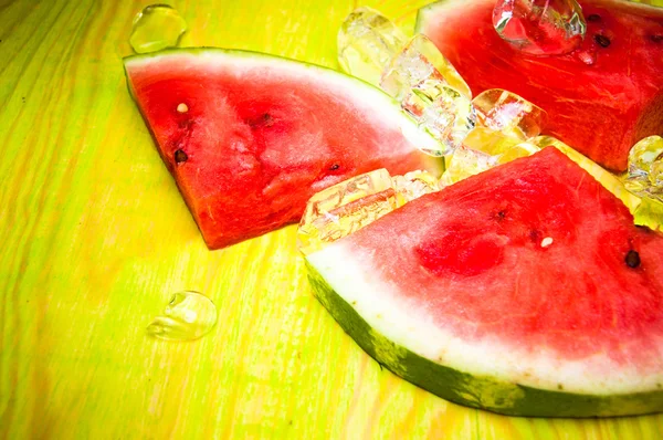 Pieces of watermelon and ice cubes on green wooden background — Stock Photo, Image