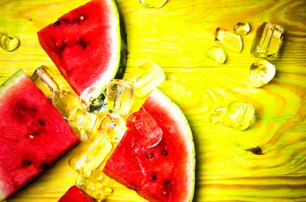 Pieces of watermelon and ice cubes on green wooden background — Stock Photo, Image