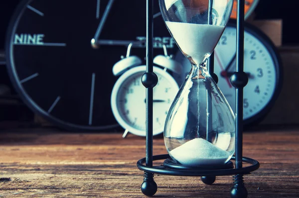 Eski ahşap masa üzerinde kum saati ve Işaretleyerek saatler