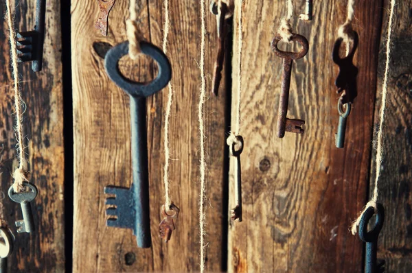 Muchas llaves colgando de una cuerda. Fondo de madera. Enfoque selectivo — Foto de Stock