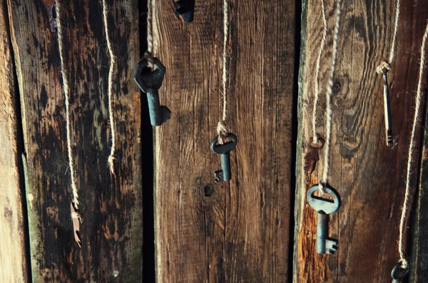 Muitas chaves penduradas em uma corda. Fundo de madeira. Foco seletivo — Fotografia de Stock