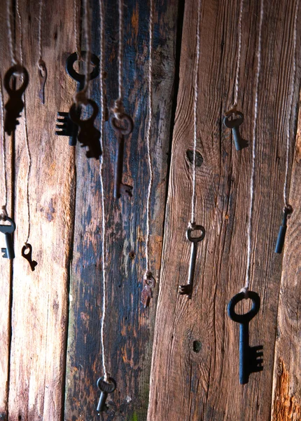 Muchas llaves colgando de una cuerda. Fondo de madera. Enfoque selectivo — Foto de Stock