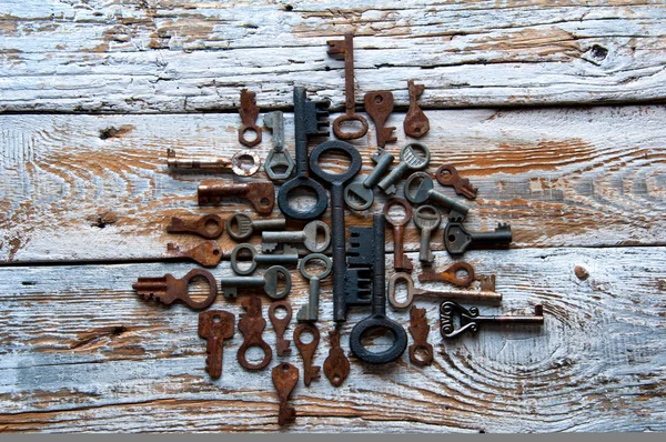 Many rusty keys and padlocks on white wood — Stock Photo, Image