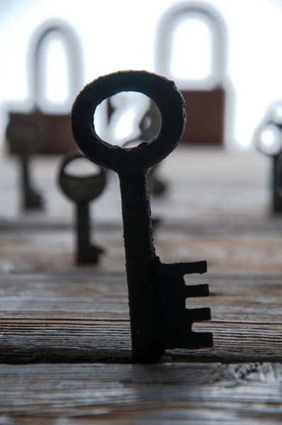 Oude roestige sleutels en hangsloten op witte houten tafel — Stockfoto