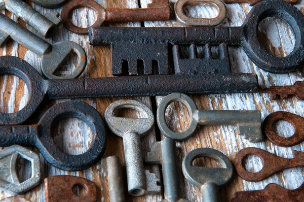 Viele rostige Schlüssel und Vorhängeschlösser auf weißem Holz — Stockfoto
