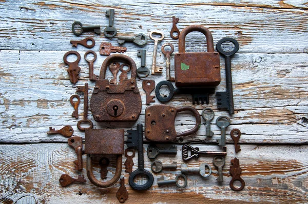 Muchas llaves oxidadas y candados en madera blanca — Foto de Stock