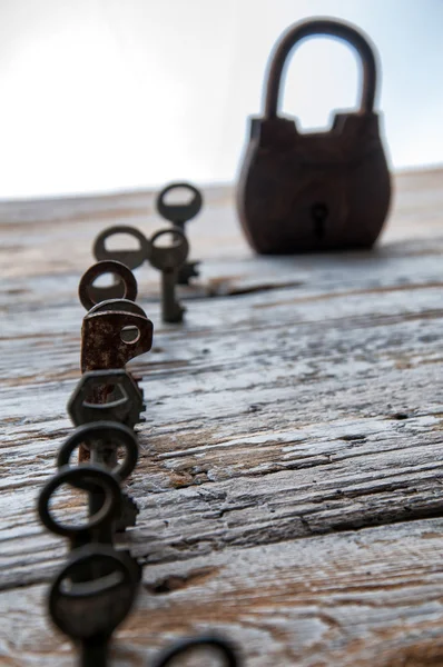 Gamla rostiga nycklar och hänglås på vitt trä bord — Stockfoto