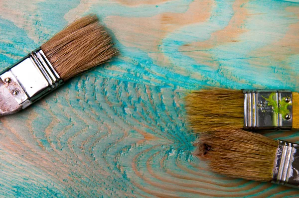 Pędzli malarstwo na niebieskim drewnianym stole — Zdjęcie stockowe