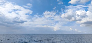 Bulutlar mavi gökyüzünde denizin üstünde