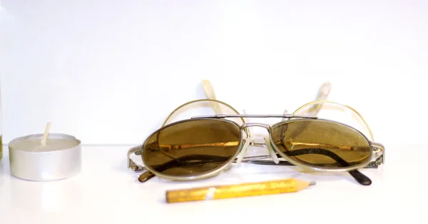 View on old sunglasses and a candle with white background — Stock Photo, Image