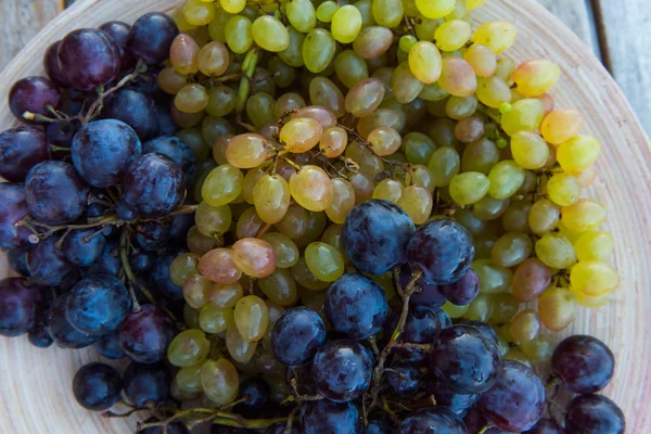 Pêssegos e uvas em um prato na mesa — Fotografia de Stock