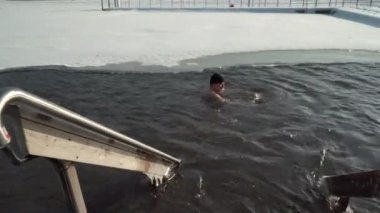 Espoo Finlandiya 'daki buz deliğinde ileri geri yüzen adamın bakışı.