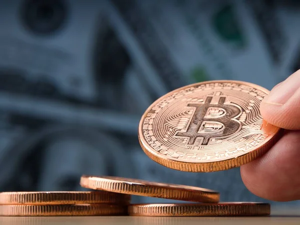 Bitcoin paralarını gösteren bir kadın el. Arka plan olarak dolar banknotları. Sanal kripto para konsepti. Bitcoins ticareti. Seçici odaklanma.