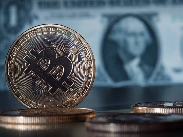 Ekonomi kavramı. Alternatif bankacılık sistemi. Bitcoin paralar masada. Arka plan olarak dolar banknotları. Seçici odaklanma. Yakın plan.