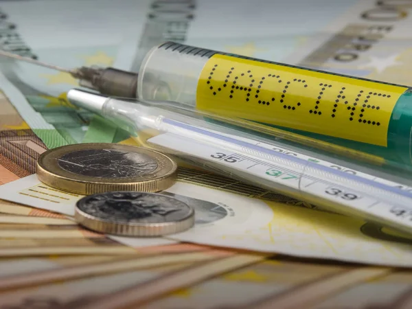 Kullanılabilirlik aşısı konsepti. İnsanlar aşı siparişini bekliyor. Paralı aşı bulmakta güçlük çekiyorlar. Bir şırınga, bir derece cam, masadaki para. Seçici odaklanma. Yakın plan.