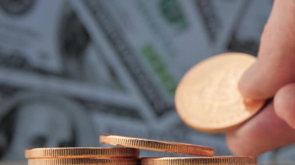 Weibliche Hand zeigt Bitcoin-Münze. Dollarnoten als Hintergrund — Stockvideo