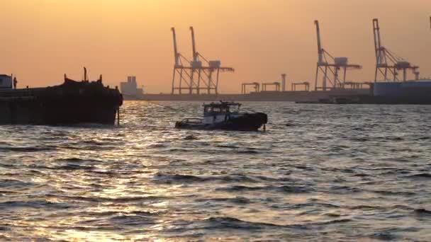 Mała łódź ciągnąca duży statek pasażerski w morzu w porcie Osaka w Japonii — Wideo stockowe