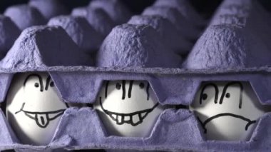 İki mavi yumurta tepsisi ve ortasında yüzleri çizilmiş yumurtalar.