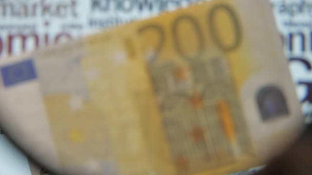 A kerek nagyító a sárga 200 eurós bankjegyen — Stock videók