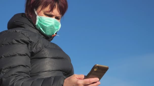 Μια άποψη της κυρίας κοιτάζοντας το τηλέφωνό της με τη μάσκα προσώπου στη Φινλανδία — Αρχείο Βίντεο