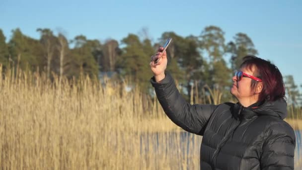 Der Blick auf die hohen Gräser auf dem Rücken mit der Dame, die in Finnland Selfies macht — Stockvideo