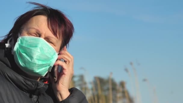 Женщина в маске разговаривает со своим работодателем по телефону в Финляндии — стоковое видео