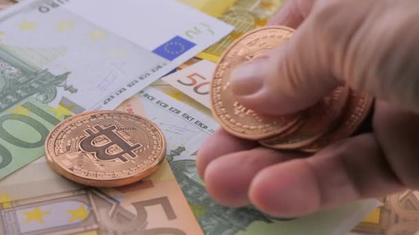 The human hand counting gold bitcoins. Crypto currency on euro banknotes — 图库视频影像